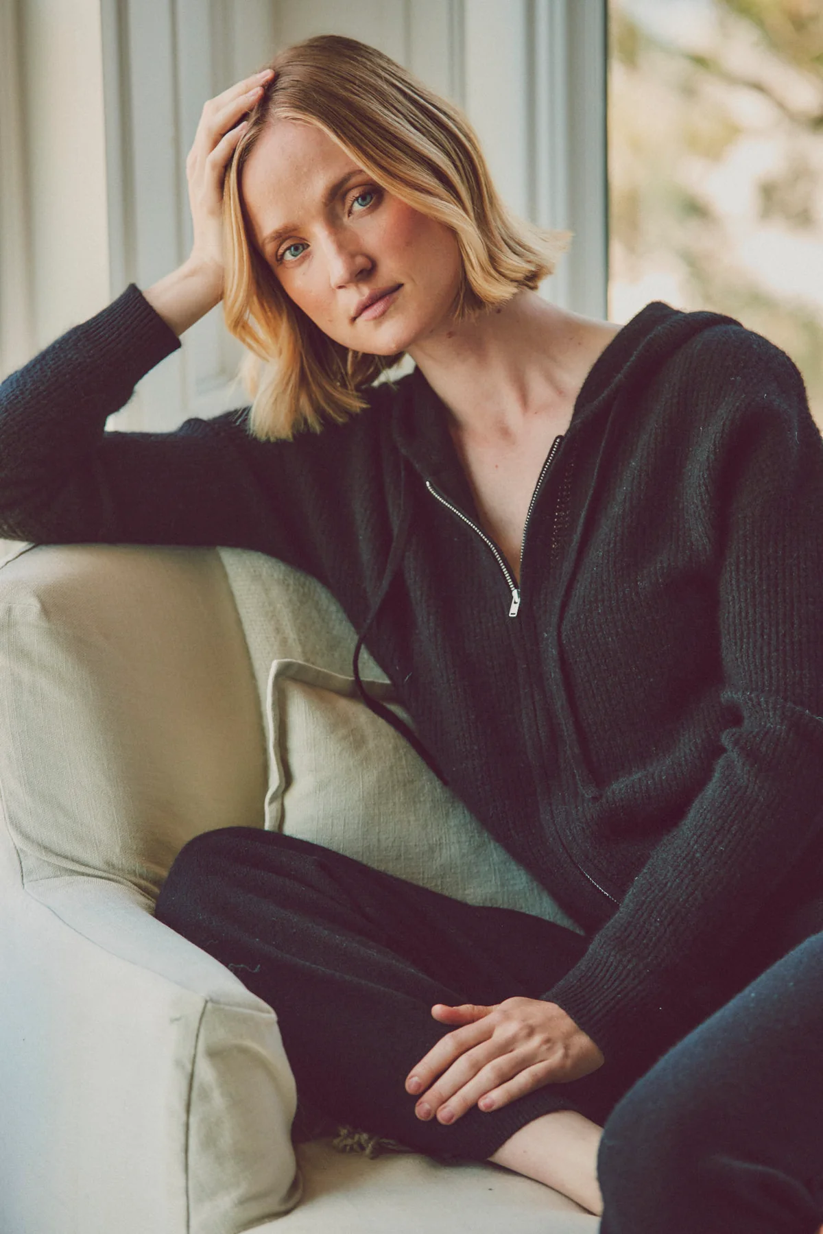 a model sitting down in a black hoodie