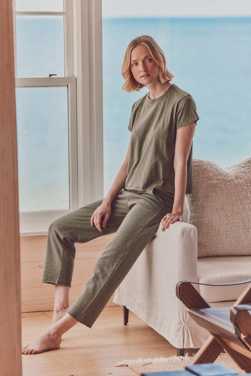 model sitting down in a green t-shirt and pants