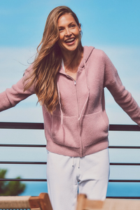 a model smiling in a pink hoodie