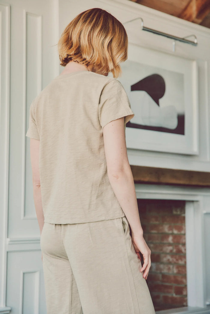 a model turned away in a beige tee and pants