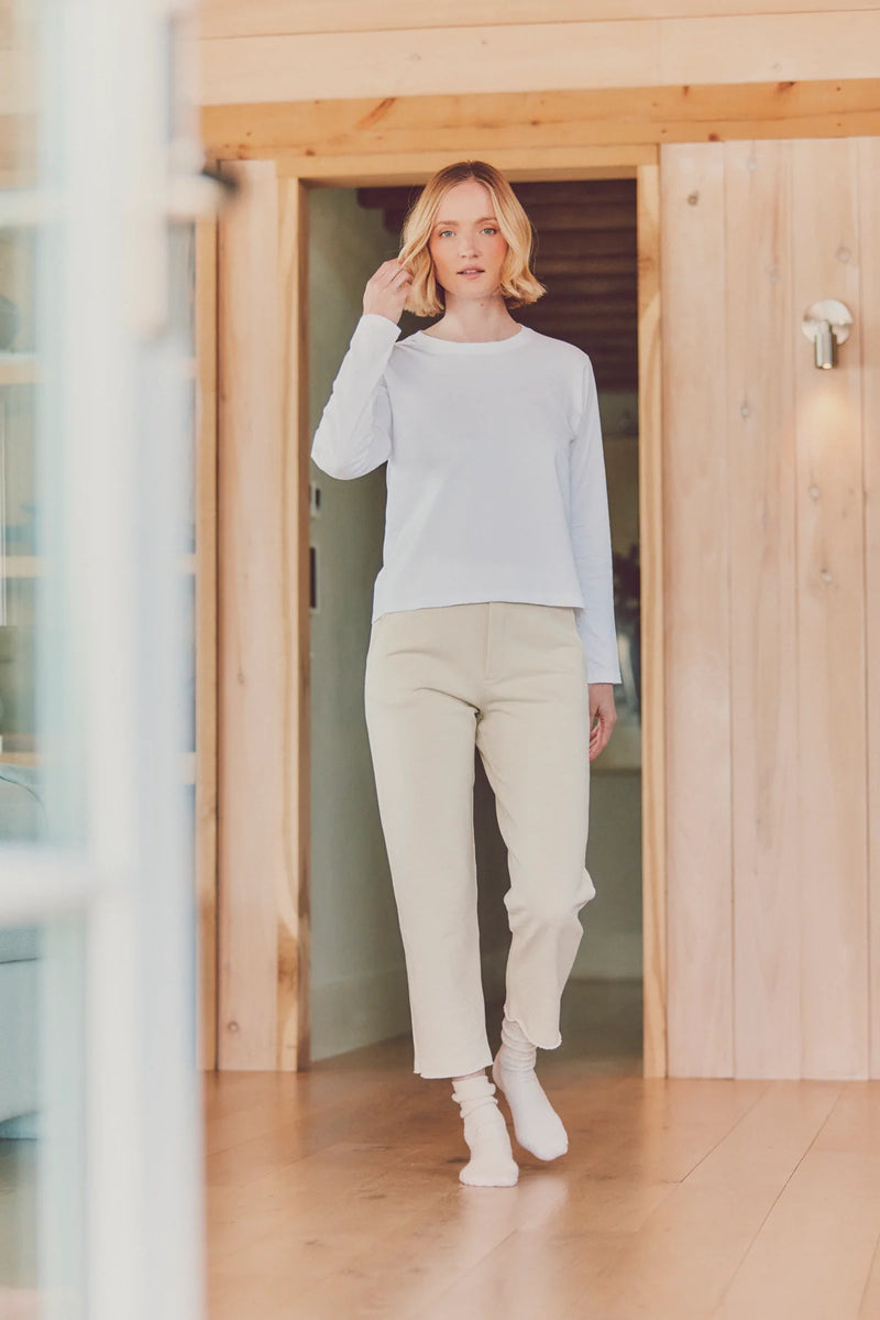 a model walking toward the camera in beige pants and a white top